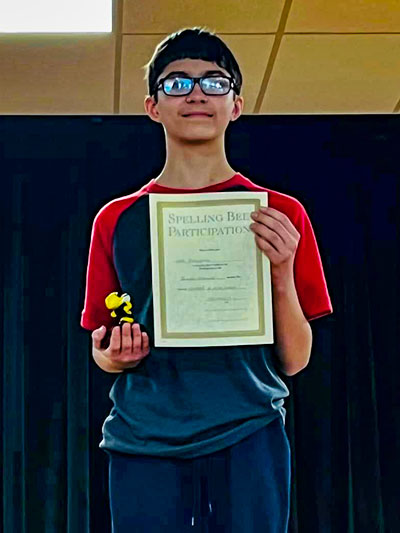 Student holding his spelling bee certificate